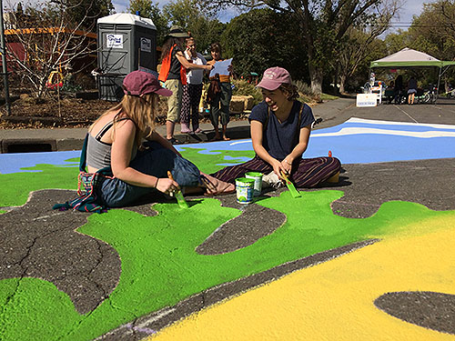 having a fun time painting the leaves to a giant oak tree for the street mural on the corner of M Street and Duke Drive in Davis, California